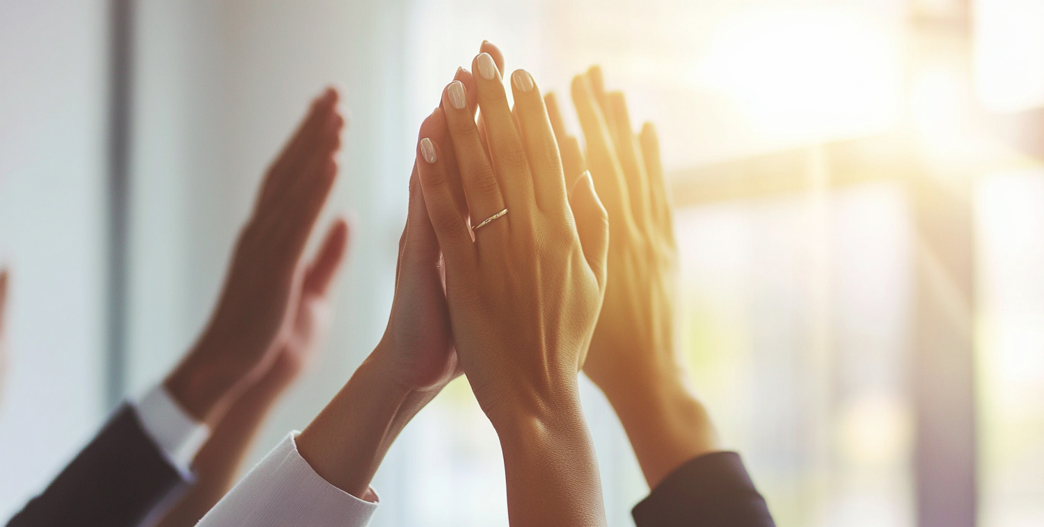 Hands raised and clapping together with warm light behind them